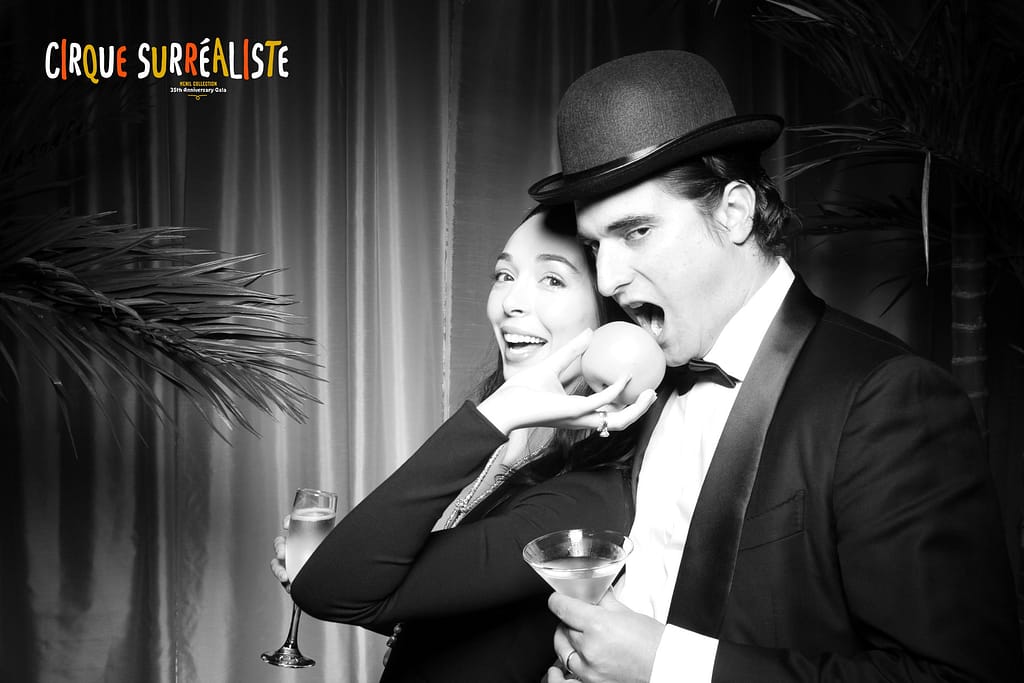 A couple poses with bowler hat and apple in a vintage photo booth photo